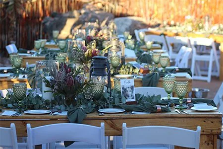 Long celebration table set with greenery and lanterns in the Boma