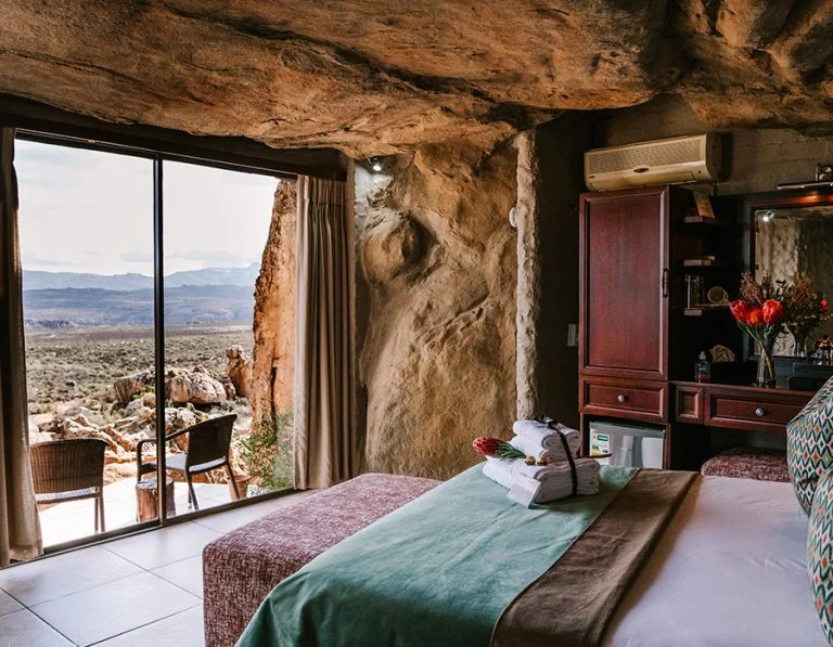 Cave Suite bedroom built beneath a natural sandstone overhang, looking across the reserve
