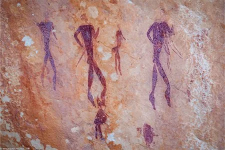 Ancient human figures painted in deep red pigment on sandstone