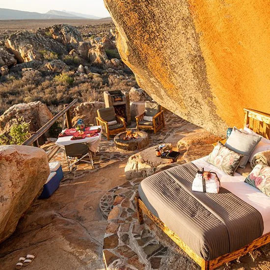 Open-air suite and fire pit sheltered beneath a monumental sandstone boulder