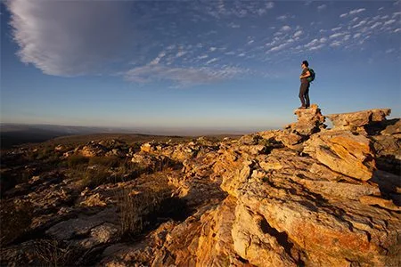 A hiker standing on a high sandstone ridge beneath an immense sky